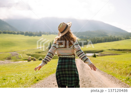 Happy female traveler exploring area in green valley with mountains in background. Concept of nature 137120486