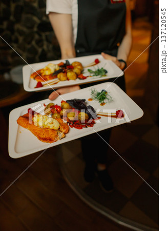 Delicious dishes on plates in the waiter's hand Delicious dishes on plates in the waiter's hand 137120545