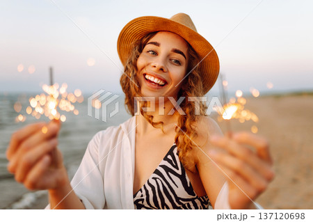 The sparklers in the hands of young woman on the beach. Holidays, vacation, relax, lifestyle concept 137120698