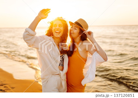 Portrait of two beautiful woman at the summer day relaxing on coast at sunset. Travel, weekend 137120851