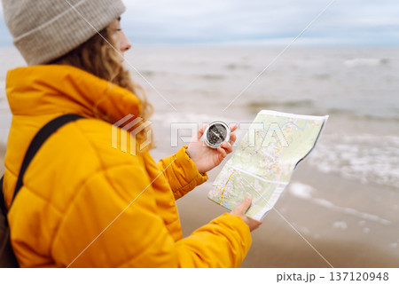 A young woman traveler with a compass and map, reading map looking for directions. Active lifestyle. A young woman traveler with a compass and map, reading map looking for directions. Active lifestyle. 137120948