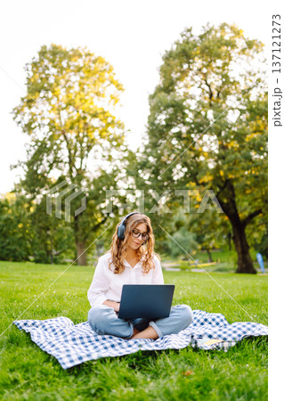 Portrait of woman sitting on green grass in park with legs crossed. Concept for education, business. Portrait of woman sitting on green grass in park with legs crossed. Concept for education, business. 137121273