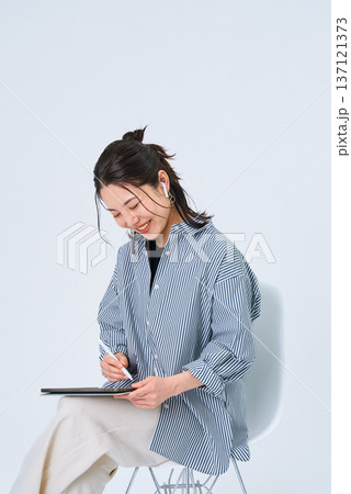 カジュアルな服装でタブレットPCを使う若い女性 カジュアルな服装でタブレットPCを使う若い女性 137121373