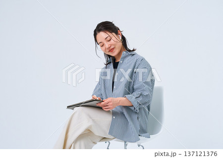 カジュアルな服装でタブレットPCを使う若い女性 カジュアルな服装でタブレットPCを使う若い女性 137121376