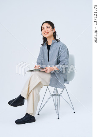 カジュアルな服装でタブレットPCを使う若い女性 カジュアルな服装でタブレットPCを使う若い女性 137121378