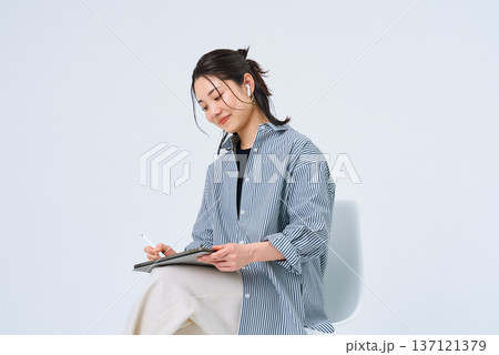 カジュアルな服装でタブレットPCを使う若い女性 カジュアルな服装でタブレットPCを使う若い女性 137121379