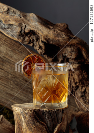 Old-fashioned cocktail with ice and dried orange slice. 137121698