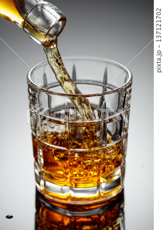 The amber-gold strong alcoholic beverage is poured into a glass. 137121702