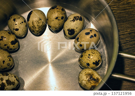 Top view of fresh speckled quail eggs arranged in a circle inside a metal bowl. Rustic food background showing organic farm produce, cooking ingredients, and healthy nutrition concept. Top view of fresh speckled quail eggs arranged in a circle inside a metal bowl. Rustic food background showing organic farm produce, cooking ingredients, and healthy nutrition concept. 137121956