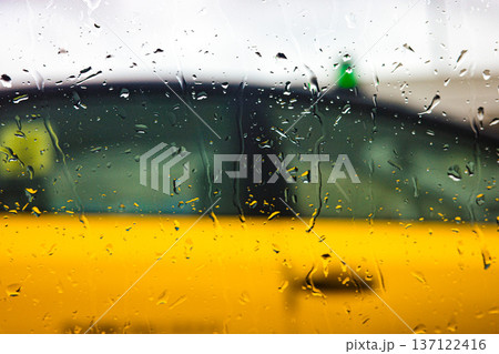 Rain drops on window glass with blurred urban background during rainy day 137122416