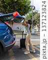 A teenager is getting ready to leave her car and is pulling out a suitcase 137123824