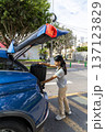 A teenager is opening the trunk of a blue car 137123829