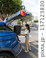 A teenager is opening the trunk of a blue car 137123830
