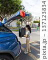 A teenager is opening the trunk of a blue car 137123834