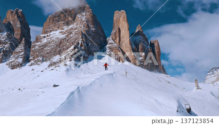 Ski mountaineer crossing a snowy ridge in the Dolomites with dramatic alpine peaks and blue sky in the background, capturing winter adventure and breathtaking mountain landscape. Ski mountaineer crossing a snowy ridge in the Dolomites with dramatic alpine peaks and blue sky in the background, capturing winter adventure and breathtaking mountain landscape. 137123854