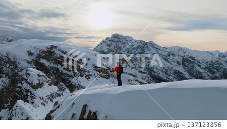 Ski mountaineer standing on a snowy cliff in the Dolomites with majestic alpine peaks in the background, capturing winter adventure, solitude and breathtaking mountain scenery. 137123856