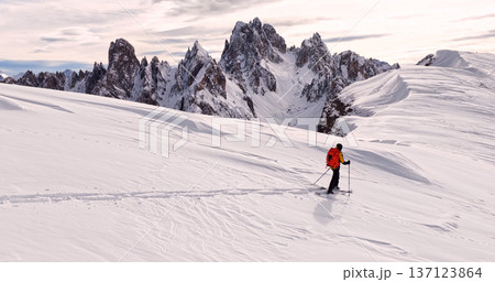Ski mountaineer crossing a snowy ridge in the Dolomites with dramatic alpine peaks and blue sky in the background, capturing winter adventure and breathtaking mountain landscape. Ski mountaineer crossing a snowy ridge in the Dolomites with dramatic alpine peaks and blue sky in the background, capturing winter adventure and breathtaking mountain landscape. 137123864