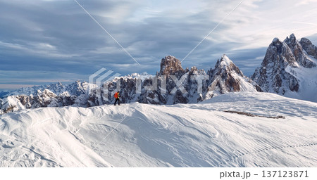 Ski mountaineer crossing a snowy ridge in the Dolomites with dramatic alpine peaks and blue sky in the background, capturing winter adventure and breathtaking mountain landscape. Ski mountaineer crossing a snowy ridge in the Dolomites with dramatic alpine peaks and blue sky in the background, capturing winter adventure and breathtaking mountain landscape. 137123871