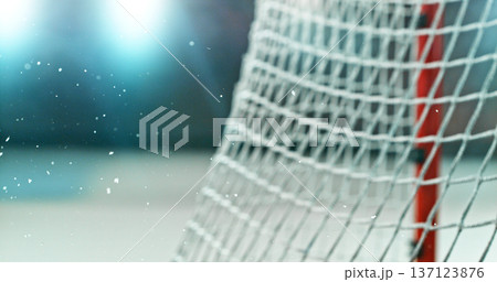 Close-up detail of an ice hockey goal net inside an indoor rink, with shallow depth of field and blurred background, capturing sports atmosphere and texture of the net mesh. Close-up detail of an ice hockey goal net inside an indoor rink, with shallow depth of field and blurred background, capturing sports atmosphere and texture of the net mesh. 137123876