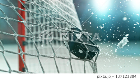 Action sports photo of a hockey puck flying into the goal net during a scoring shot, with ice particles in the air, capturing speed and intensity. Action sports photo of a hockey puck flying into the goal net during a scoring shot, with ice particles in the air, capturing speed and intensity. 137123884