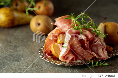 Prosciutto with pears and thyme on a silver tray. Prosciutto with pears and thyme on a silver tray. 137124008