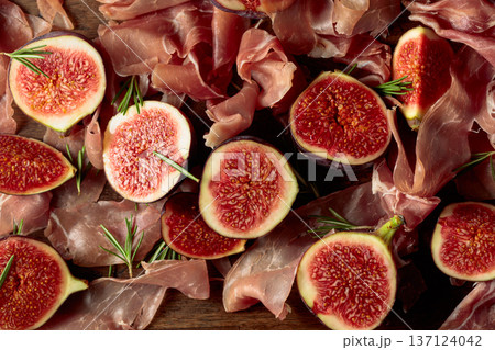 Prosciutto with rosemary and fig fruit on an old wooden table. Prosciutto with rosemary and fig fruit on an old wooden table. 137124042
