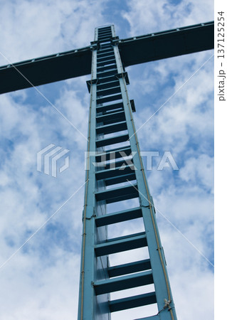 Metal Ladder Leading Up to Industrial Structure Against Cloudy Sky Metal Ladder Leading Up to Industrial Structure Against Cloudy Sky 137125254