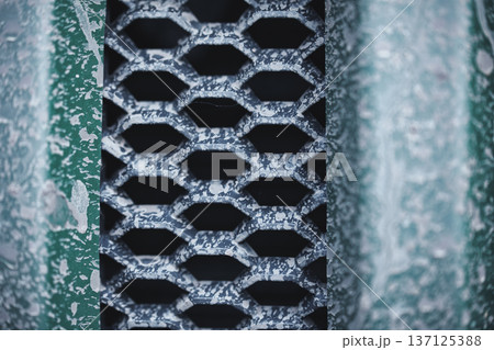 Weathered Metal Vent Grid Macro Texture Close-up of old painted metal grille with peeling paint and corrosion forming abstract industrial pattern 137125388