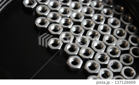 Iron nuts on a black flat surface are huddled together on the right side of the image 137126009