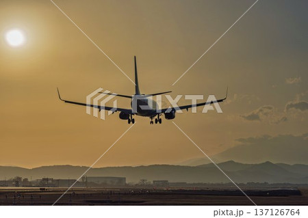 夕暮れの仙台空港　夕日と着陸中の飛行機　宮城県名取市 137126764
