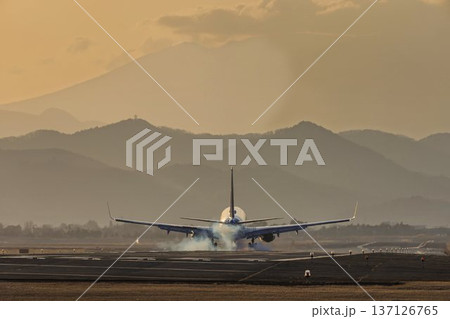 夕暮れの仙台空港　夕日と着陸中の飛行機　宮城県名取市 137126765