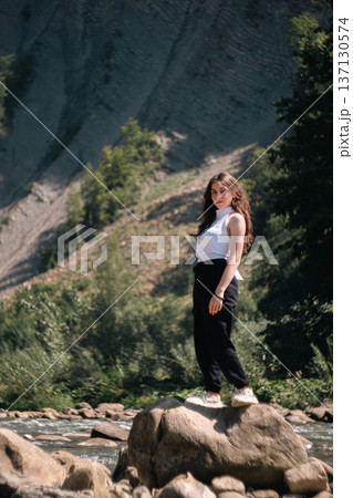 Young Woman Standing on Rock by Mountain River in Summer Nature 137130574