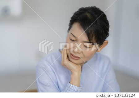 頬杖をつく50代後半の女性 頬杖をつく50代後半の女性 137132124