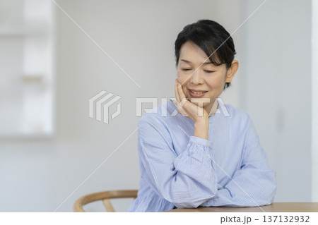 頬杖をついてうつむく50代後半の女性 137132932