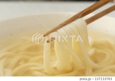 湯気の立った温かいうどんを箸で持ち上げる 137133763