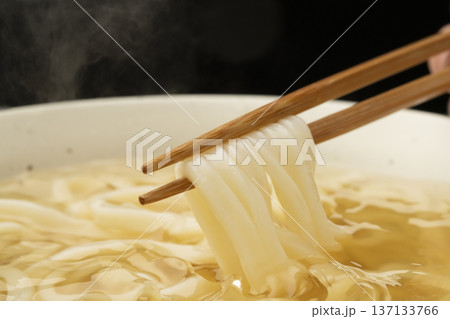 湯気の立った温かいうどんを箸で持ち上げる 137133766