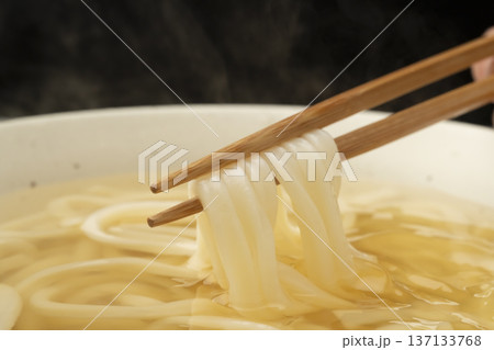 湯気の立った温かいうどんを箸で持ち上げる 137133768
