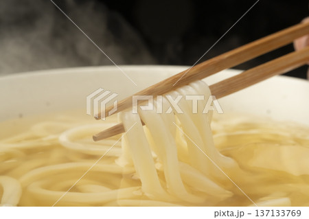湯気の立った温かいうどんを箸で持ち上げる 137133769