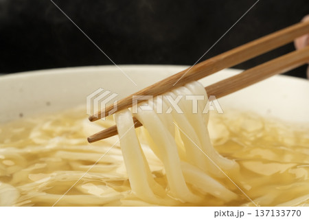 湯気の立った温かいうどんを箸で持ち上げる 137133770