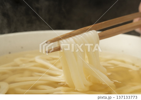湯気の立った温かいうどんを箸で持ち上げる 137133773