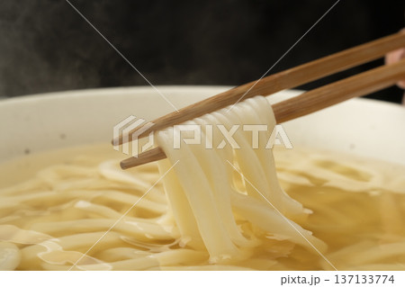 湯気の立った温かいうどんを箸で持ち上げる 湯気の立った温かいうどんを箸で持ち上げる 137133774
