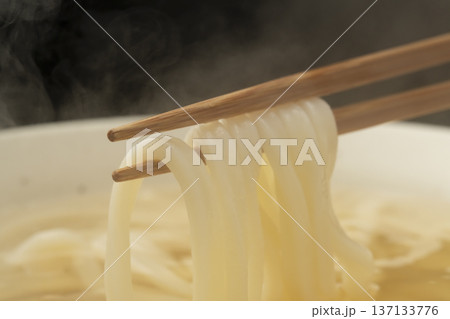 湯気の立った温かいうどんを箸で持ち上げる 137133776