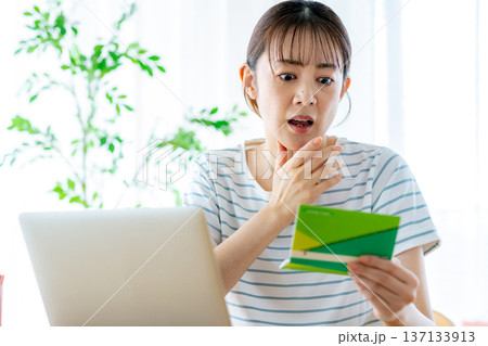 通帳を見てため息をつく主婦 137133913