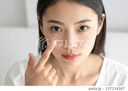 コンタクトレンズを指にのせている女性 137134367
