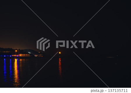 Moonlight Over Sea Waves Full Moon Glow ocean waves on sandy beach at night wooden pier. The moon illuminates water surface. Concept of beach vacation slowing down on seacoast 137135711