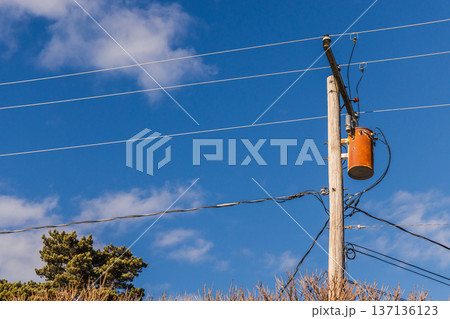 Electric transformer on wooden utility pole in USA with power lines and blue sky 137136123