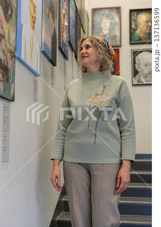 Woman appreciating contemporary art inside modern museum space and while viewing framed paintings. Woman appreciating contemporary art inside modern museum space and while viewing framed paintings. 137136599