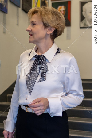 Woman appreciating contemporary art inside modern museum space and while viewing framed paintings. 137136604