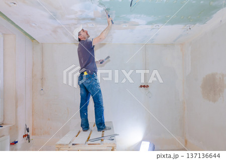 Worker make repairs in new apartment. Man plaster walls and ceilings. High quality photo Worker make repairs in new apartment. Man plaster walls and ceilings. High quality photo 137136644
