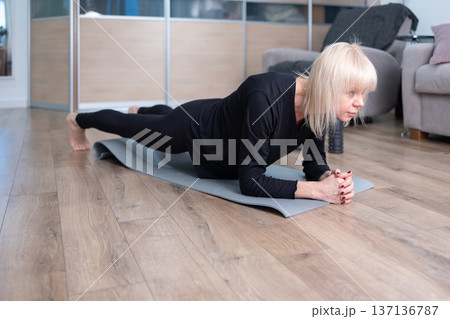 Stability Training. Woman exercising on yoga mat at home in modern living room with calm focused posture. 137136787